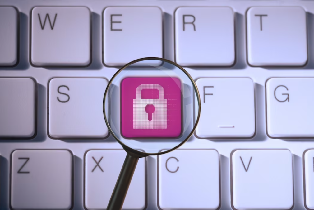 white keyboard and magnifying glass on pink security sign