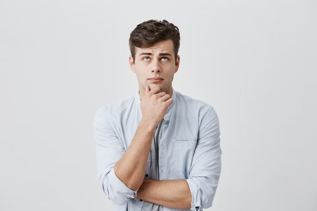 Man pondering with hand on chin, gazing upward in thought