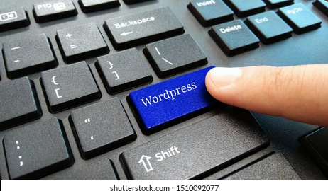 Image of a black laptop keyboard with a blue 'WordPress' key and a hand hovering above it